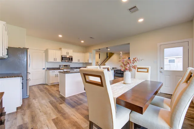 a living room with stainless steel appliances kitchen island granite countertop furniture wooden floor and a kitchen view