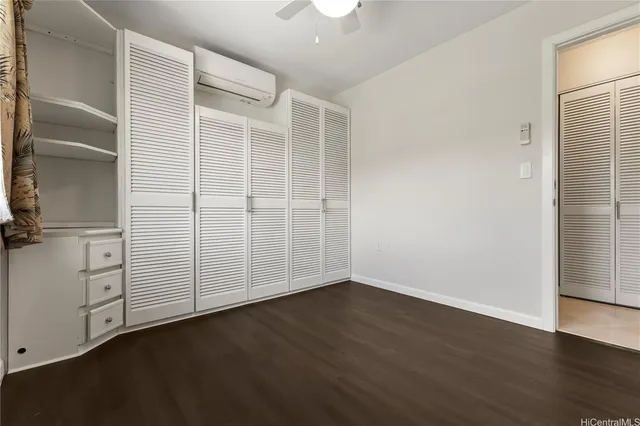 an empty room with wooden floor closet and windows