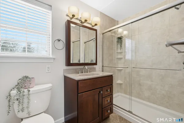 a bathroom with a granite countertop sink toilet a mirror and shower