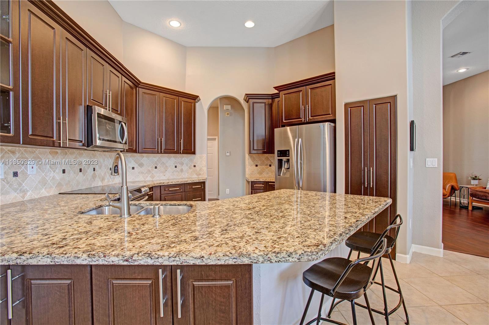 3060 Southwest 195th Terrace Miramar, FL 33029 - Photo 35 of 76 a kitchen with kitchen island granite countertop wooden cabinets and refrigerator