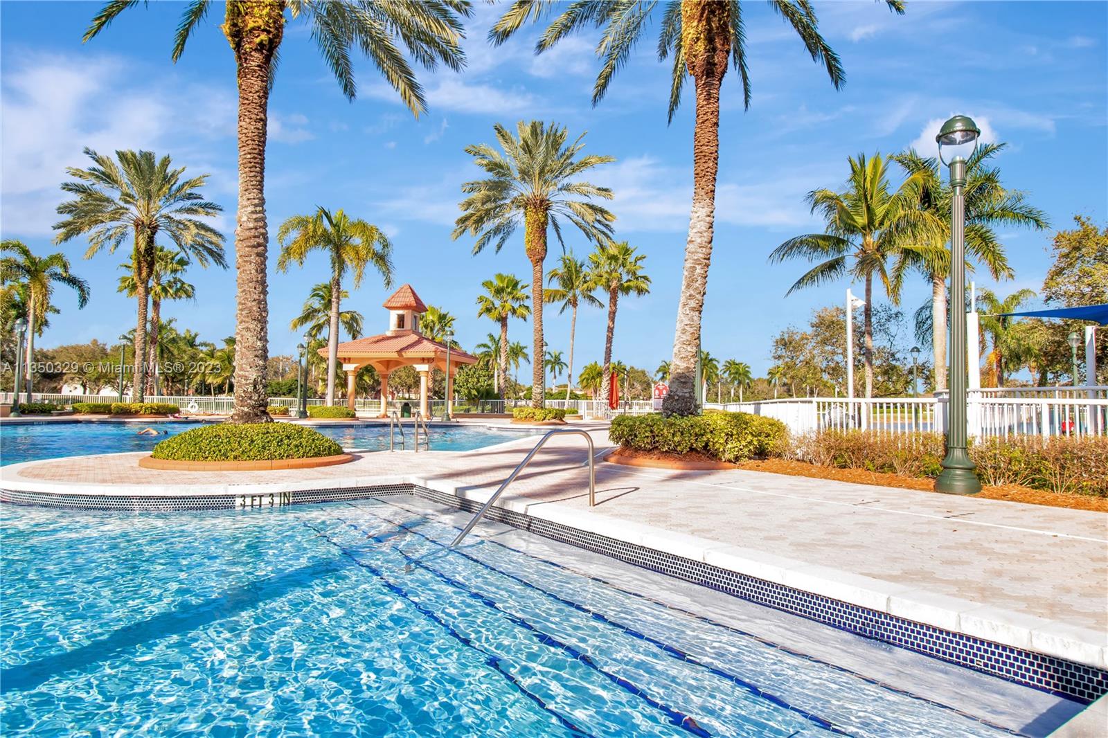 3060 Southwest 195th Terrace Miramar, FL 33029 - Photo 65 of 76 a view of a swimming pool with a lawn chairs under palm trees