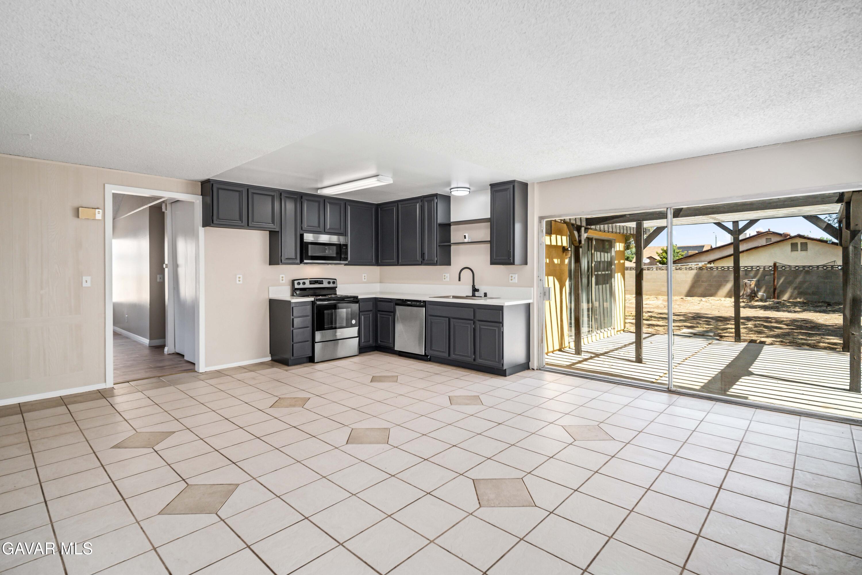 1027 Caperton Street Lancaster, CA 93535 - Photo 15 of 30 a large white kitchen with cabinets and a sink