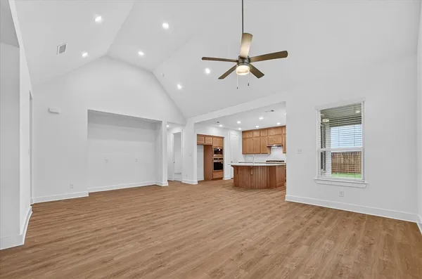 a view of an empty room with a window and wooden floor
