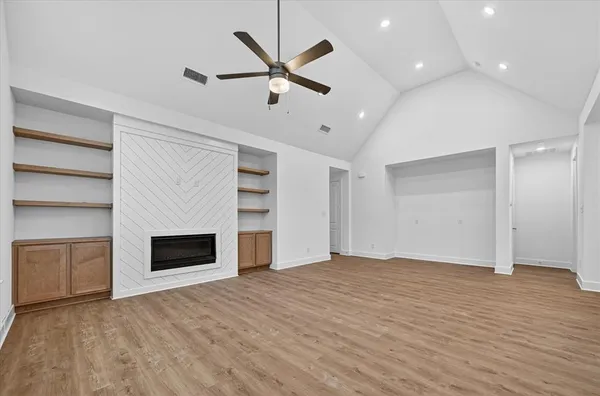 a view of empty room with kitchen and fireplace
