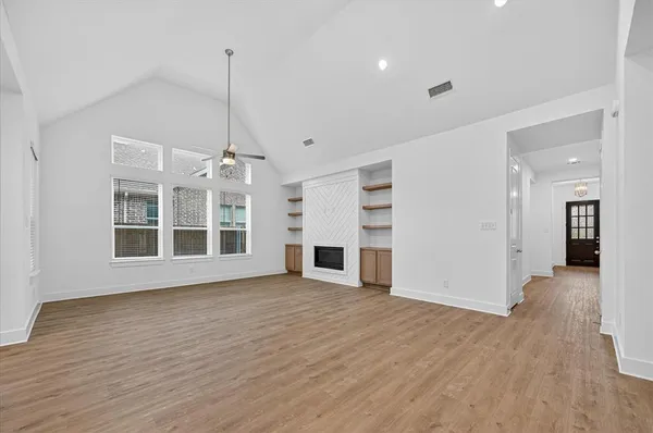 a view of a big room with wooden floor fire place and windows