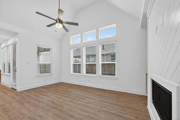 a view of an empty room with wooden floor fireplace and a window