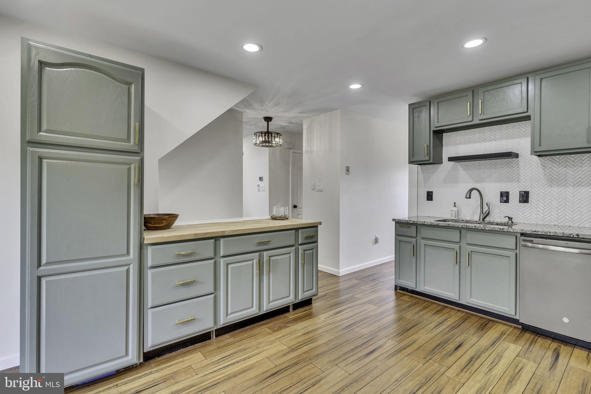 6546 Cornell Road Bryans Road, MD 20616 - Photo 10 of 35 a kitchen with stainless steel appliances granite countertop a refrigerator a sink and white cabinets with wooden floor
