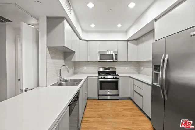 a kitchen with stainless steel appliances granite countertop refrigerator a sink a stove top oven and a dishwasher