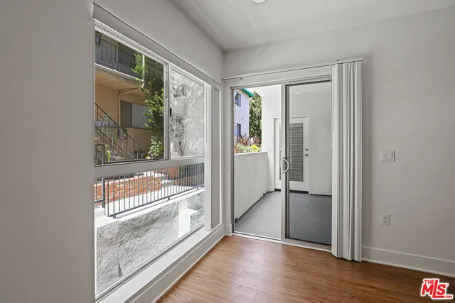 a view of front door and bedroom with wooden floor