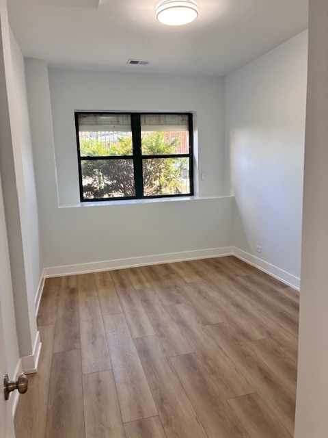 8010 South Ridgeland Avenue, Unit 1D Chicago, IL 60617 - Photo 26 of 28 an empty room with wooden floor and windows