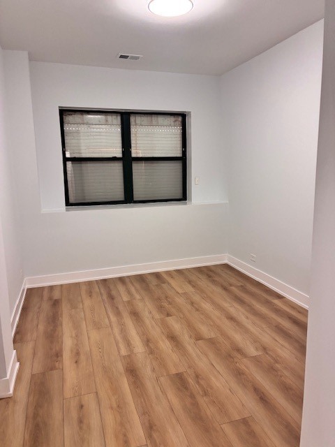 8010 South Ridgeland Avenue, Unit 1D Chicago, IL 60617 - Photo 27 of 28 a view of an empty room with wooden floor and a window