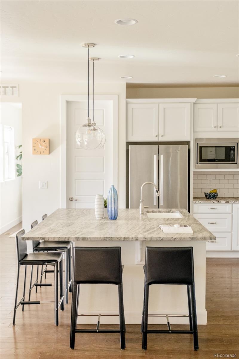 11880 West 38th Place Wheat Ridge, CO 80033 - Photo 8 of 30 a kitchen with stainless steel appliances granite countertop a kitchen island and chairs in it