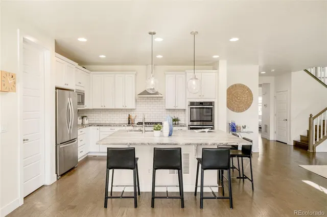 a kitchen with stainless steel appliances a dining table chairs a sink and a refrigerator