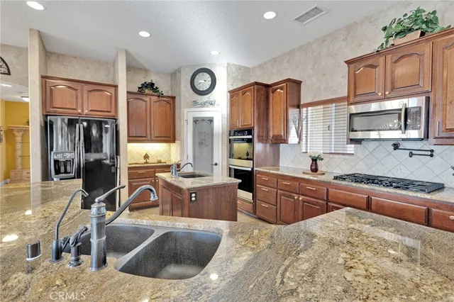 a large kitchen with stainless steel appliances granite countertop a sink and a stove top oven