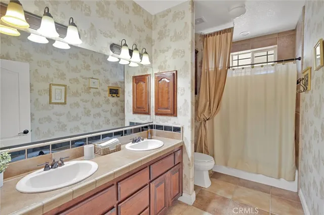 a bathroom with a granite countertop double vanity sink a mirror and a shower