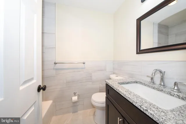 a bathroom with a granite countertop sink toilet and mirror