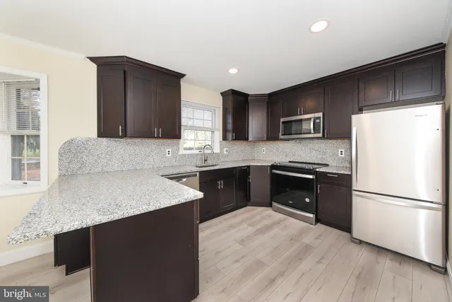 a kitchen with stainless steel appliances granite countertop a refrigerator a sink a stove a microwave and cabinets