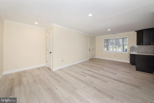 a view of an empty room with window and wooden floor
