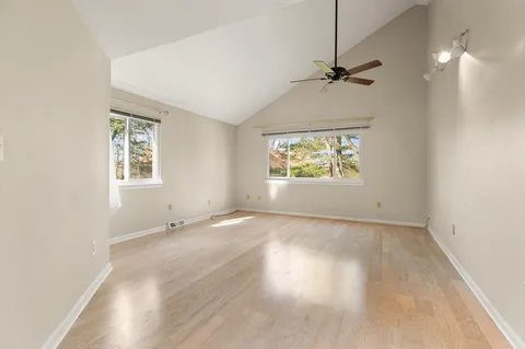 an empty room with windows and ceiling fan
