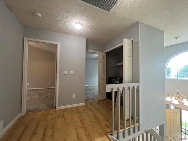 an empty room with wooden floor mirror and windows