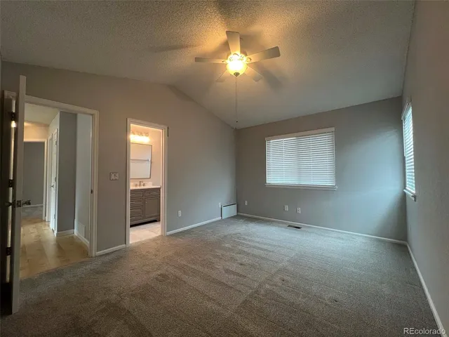 an empty room with chandelier fan and windows