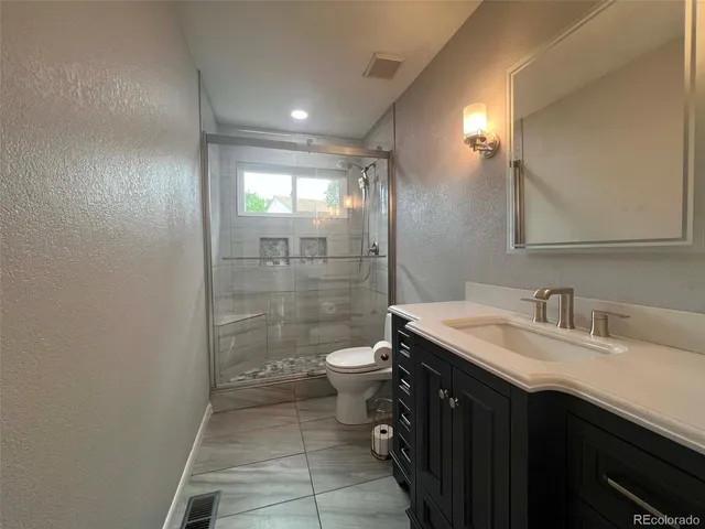a bathroom with a granite countertop sink toilet and shower