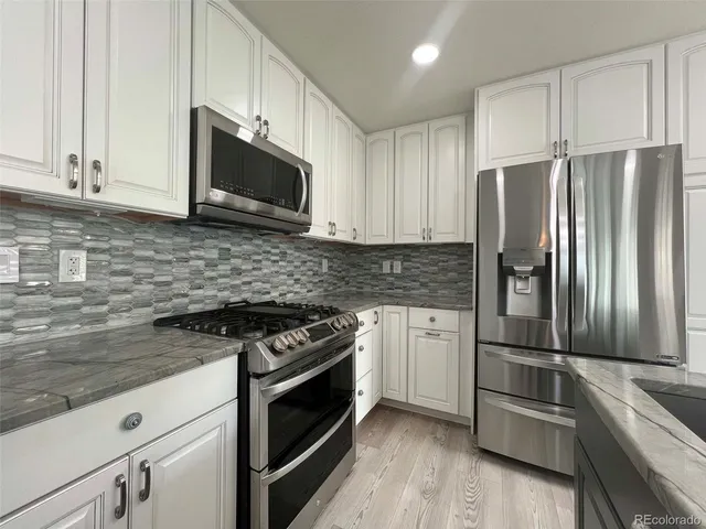 a kitchen with granite countertop a refrigerator stove and microwave