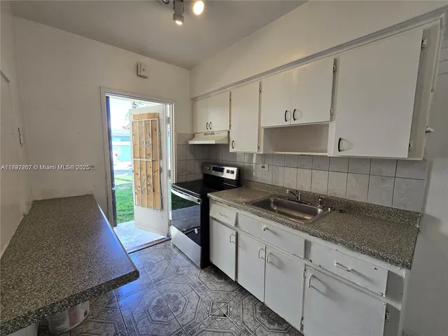 a kitchen with granite countertop a stove a sink and a refrigerator