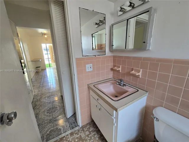 a bathroom with a granite countertop sink a toilet and mirror