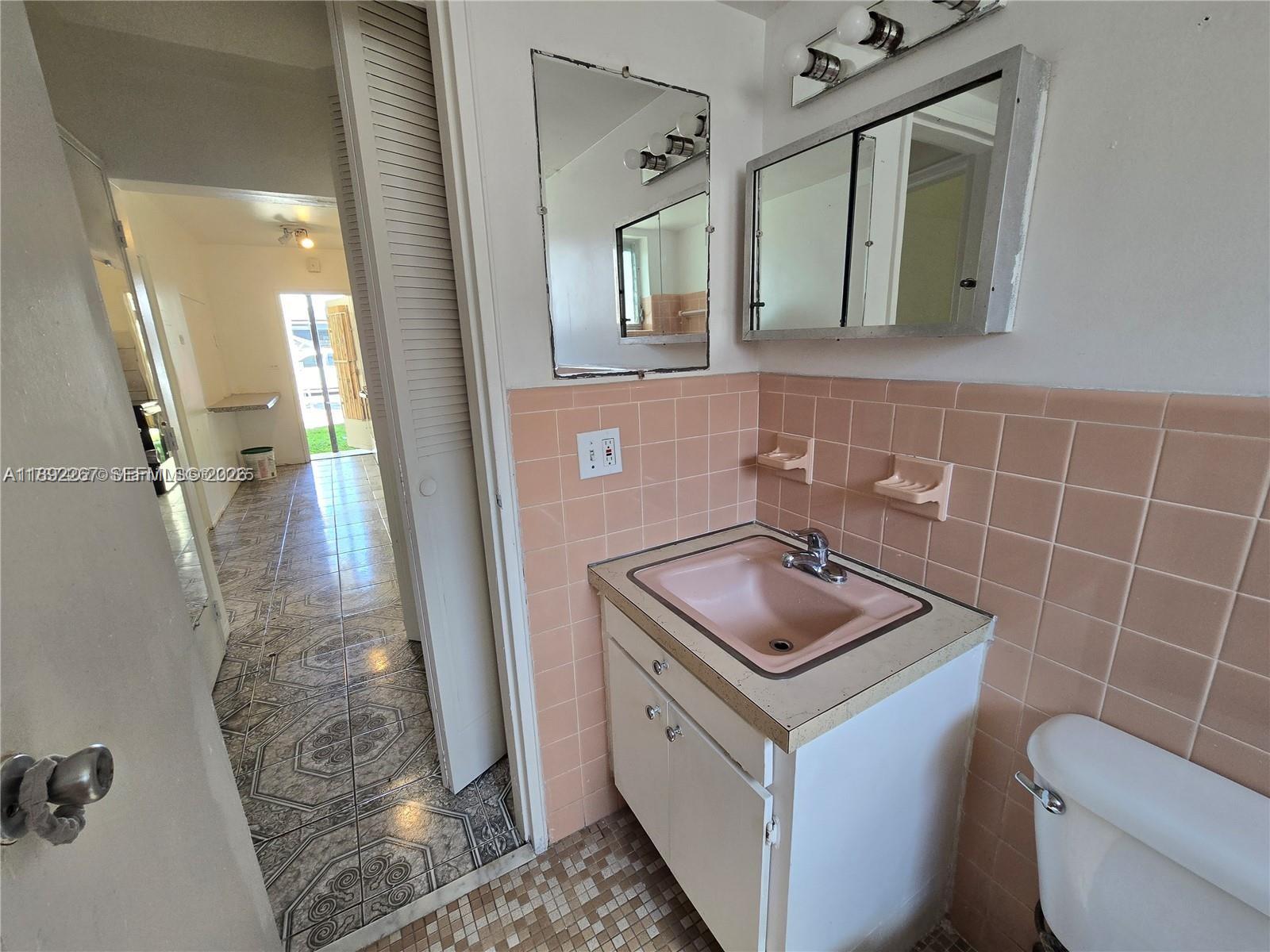 70 Northwest 77th Street, Unit 11 Miami, FL 33150 - Photo 2 of 16 a bathroom with a granite countertop sink a toilet and mirror