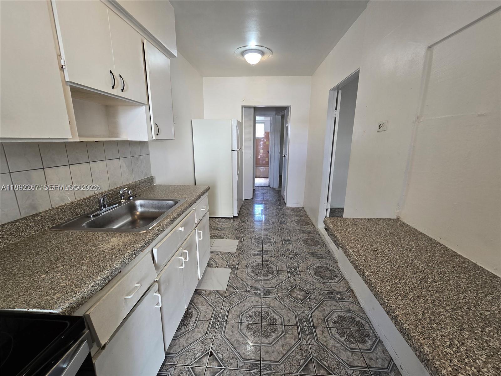 70 Northwest 77th Street, Unit 11 Miami, FL 33150 - Photo 9 of 16 a kitchen with a sink stove and cabinets