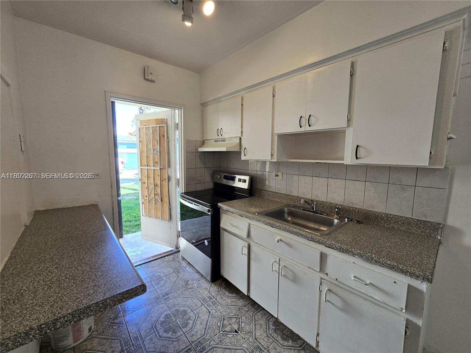70 Northwest 77th Street, Unit 11 Miami, FL 33150 - Photo 10 of 16 a kitchen with granite countertop a stove a sink and a refrigerator