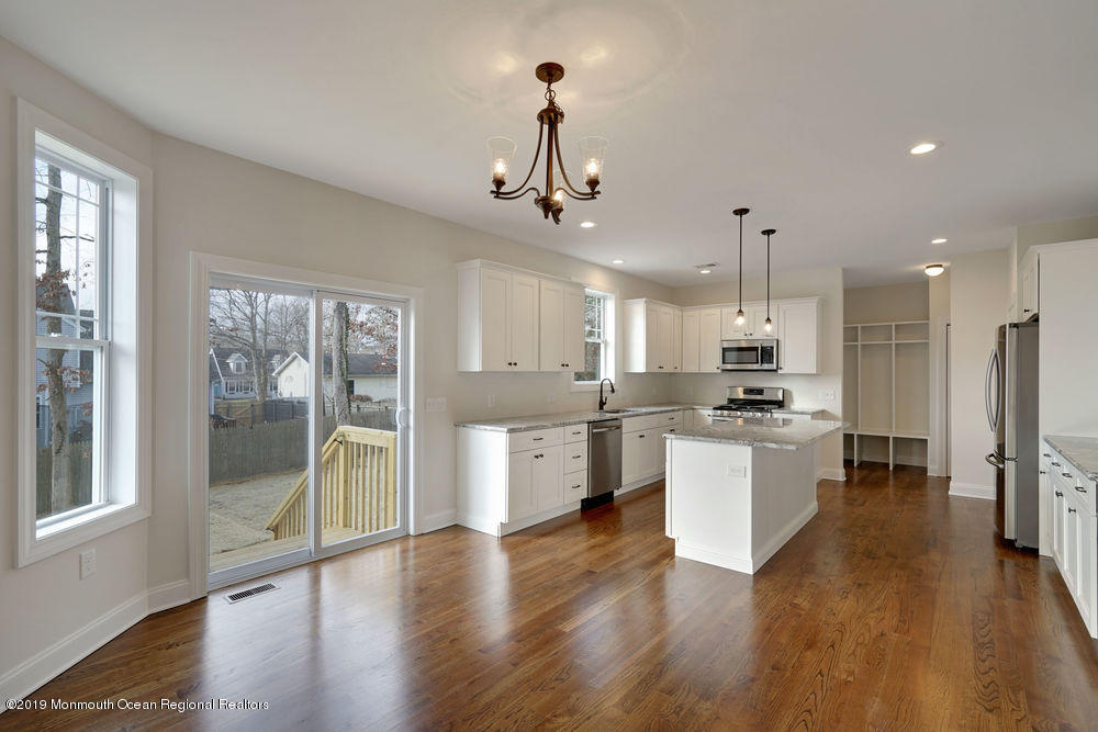 113 Lanyard Road Manahawkin, NJ 08050 - Photo 23 of 71 a large white kitchen with a refrigerator a sink dishwasher a stove and a dining table with wooden floor