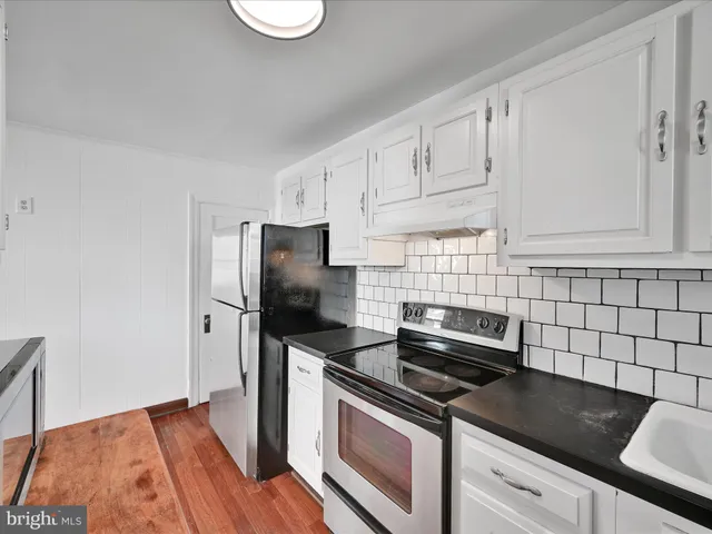 a kitchen with stainless steel appliances granite countertop a refrigerator a stove a sink and white cabinets