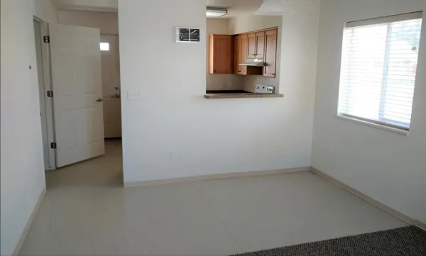 wooden floor in an empty room with a window and a kitchen