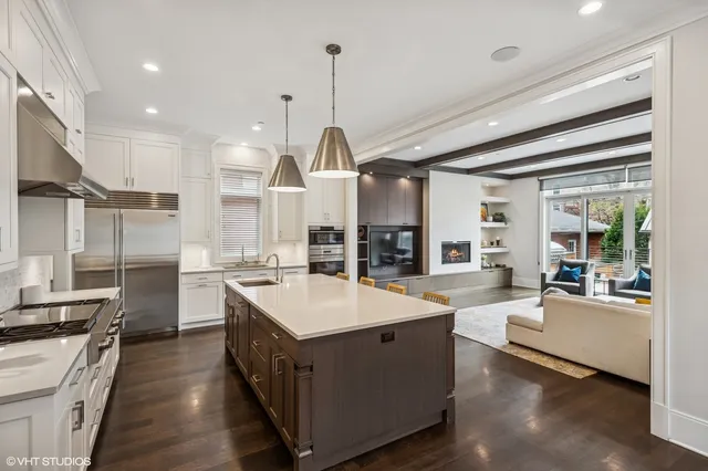 a kitchen with stainless steel appliances a stove a sink a kitchen island with chairs and wooden cabinets