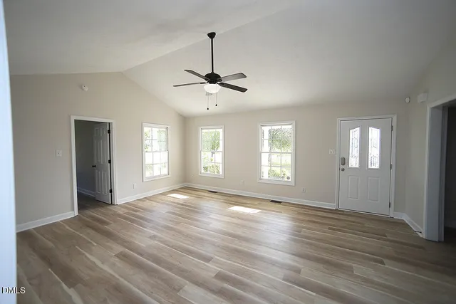a view of an empty room with a window and wooden floor