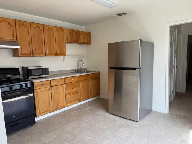 a kitchen with stainless steel appliances granite countertop a refrigerator a stove a sink and a refrigerator with wooden cabinets