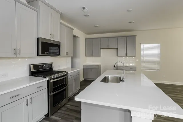 a kitchen with sink a microwave a stove and cabinets