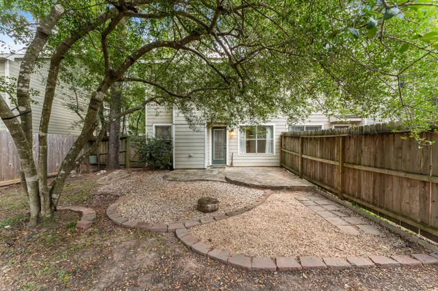 a view of a backyard with large trees and wooden fence
