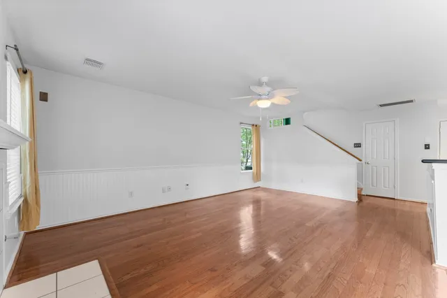 an empty room with wooden floor and windows
