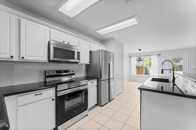 a kitchen with granite countertop a sink appliances and cabinets