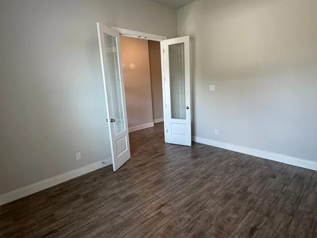 an empty room with wooden floor and entrance