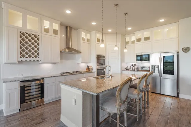 a kitchen with stainless steel appliances granite countertop a stove top oven a sink refrigerator and cabinets