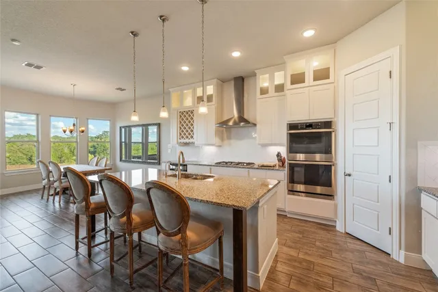 a kitchen with kitchen island granite countertop wooden floors and white cabinets