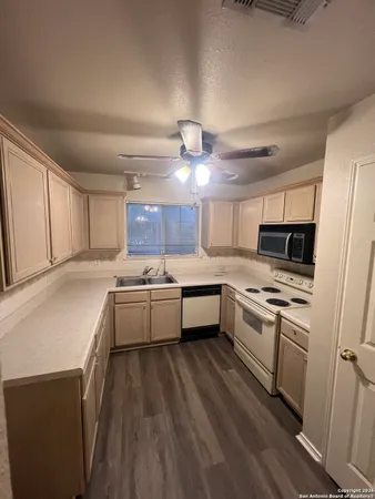 a large kitchen with a stove a sink dishwasher and a refrigerator with wooden floor