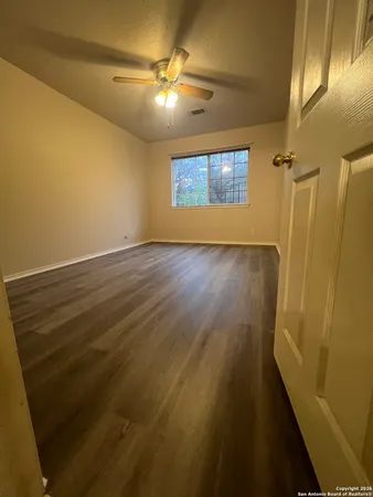 en empty room with wooden floor and fan