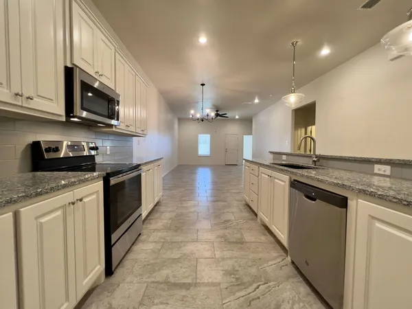 a kitchen with stainless steel appliances granite countertop a sink a stove oven and a granite counter top