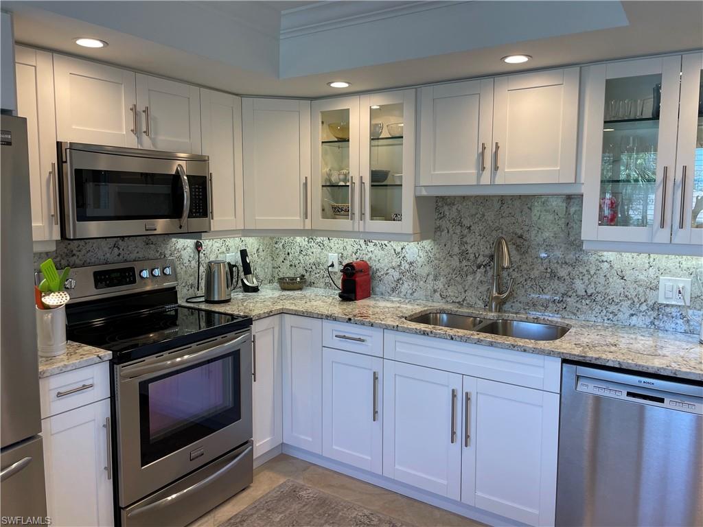 261 Quails Nest Road, Unit 6 Naples, FL 34112 - Photo 13 of 32 a kitchen with granite countertop white cabinets sink and stainless steel appliances