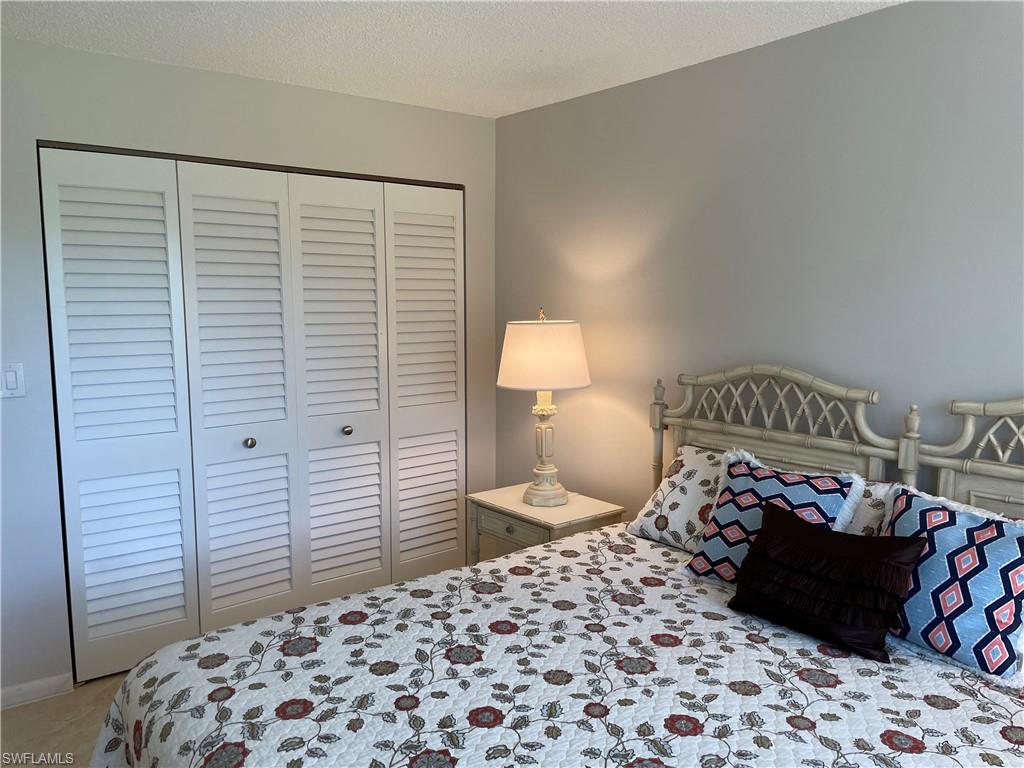 261 Quails Nest Road, Unit 6 Naples, FL 34112 - Photo 24 of 32 a bedroom with a bed and a lamp